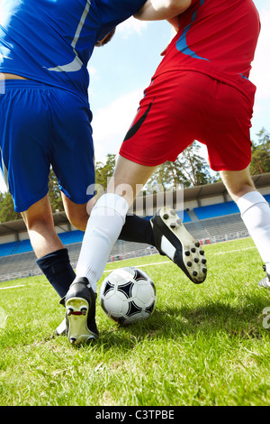 Vertical image de ballon sur le terrain de football avec les jambes essayant de Kick it Banque D'Images