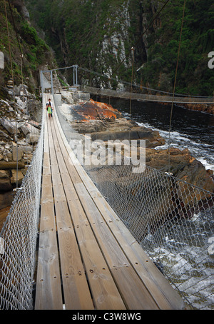 Mère et fille traversant le pont suspendu à l'embouchure de la rivière ; strorms ; Tsitsikamma Western Cape Afrique du Sud ; Banque D'Images