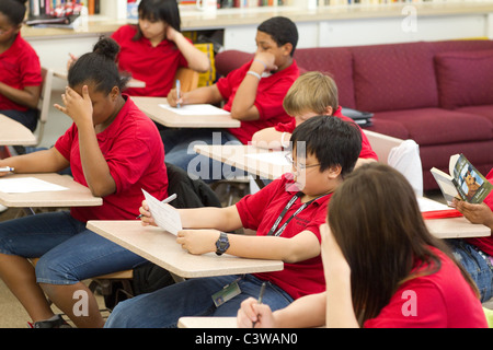 Hispaniques et Afro-américaines d'Anglo, garçons et filles prendre quiz à leur bureau pendant les cours à l'Académie Rapoport Banque D'Images