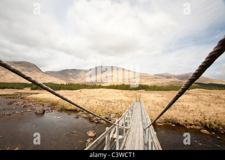 Un pont suspendu au-dessus de l'hôtel nam Beathach dans Glen Orchy, Écosse, Royaume-Uni, à la recherche jusqu'à l'Munro d'un Odhair Stob Dromore West. Banque D'Images