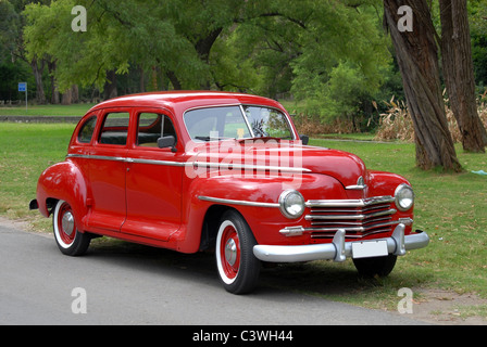 Voiture rouge antique sur fond de vert des arbres Banque D'Images