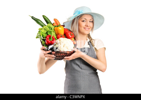 Une agricultrice tenant un panier plein de légumes Banque D'Images