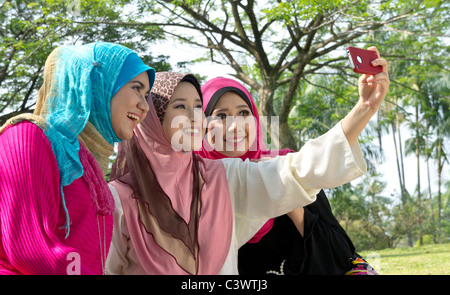 De jolies jeunes femmes musulmanes en Asie foulard sourit tout en prenant leur photo à l'aide de smart phone Banque D'Images