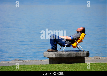 L'homme dans une chaise longue, au bord du lac, au soleil Banque D'Images