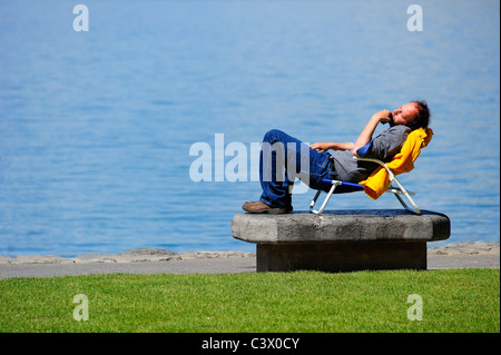 L'homme dans une chaise longue, au bord du lac, au soleil Banque D'Images
