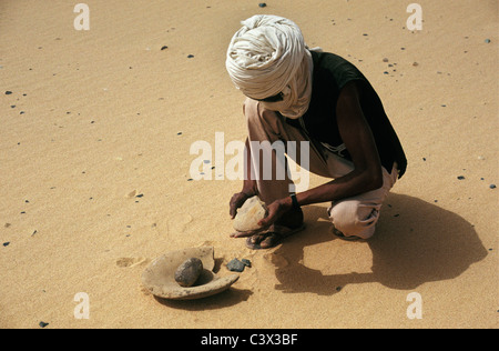 L'Algérie, Djanet. L'homme de tribu touareg. Mortier préhistorique. Désert du Sahara. Banque D'Images