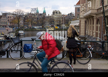 Faire du vélo à travers un pont sur un canal à Amsterdam Banque D'Images