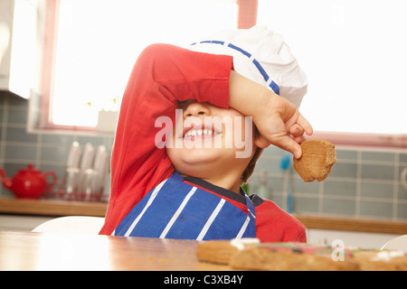 Young boy eating cookie dans la cuisine Banque D'Images