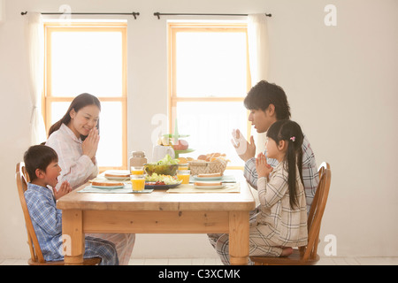 Famille de quatre personnes priaient à table de petit déjeuner Banque D'Images