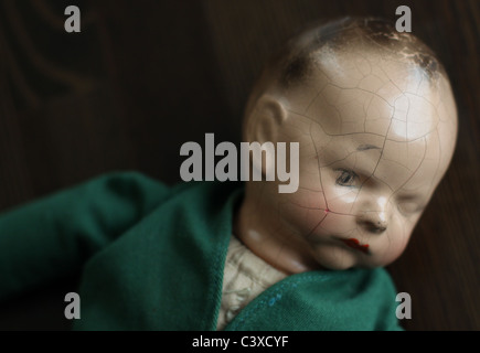 Un gros plan d'une vieille poupée de porcelaine avec un visage fissuré. Banque D'Images