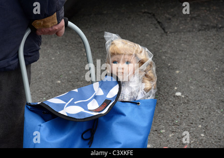 Une poupée de l'enfant dans un sac de plastique qui sort d'un panier. Banque D'Images