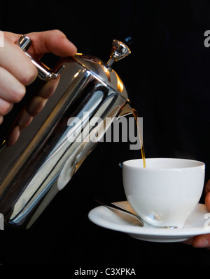 Restaurant de fine cuisine. L'on verse du café dans une cafetière à piston par un serveur. Banque D'Images