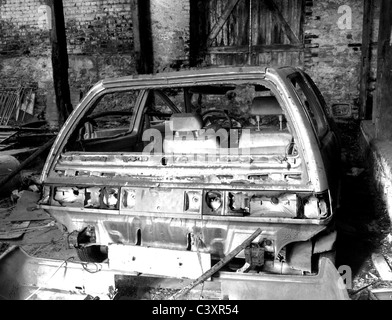 Carcasse de voiture laissée négligé dans l'épave grange, noir et blanc Banque D'Images