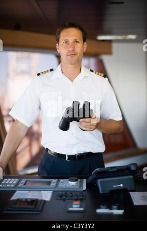 Le capitaine holding binoculars dans ses mains Banque D'Images