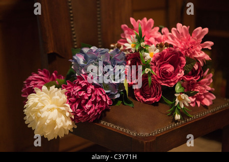 Bouquet de fleurs de soie affichée sur une chaise en cuir dans la salle de séjour. Banque D'Images