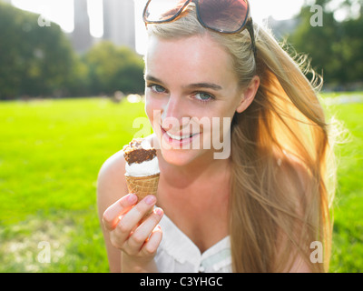 Femme mangeant une glace dans un parc Banque D'Images