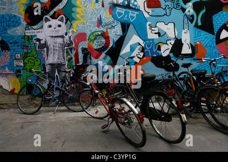 Vélos garés à côté d'un mur couvert de murs peints dans le quartier central de Mitte à Berlin Allemagne Banque D'Images