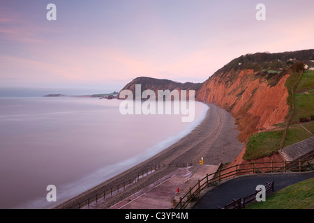 Aube du ciel rose au-dessus des crêtes et les rochers de grès rouge de Sidmouth, Jurassic Coast, Devon, Angleterre. Banque D'Images