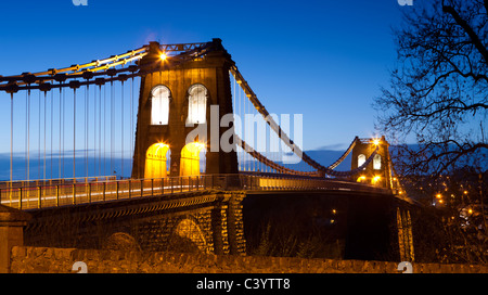 Illuminations en soirée sur le Pont Suspendu de Menai enjambant le détroit de Menai, Bangor, au nord du Pays de Galles, Royaume-Uni. Printemps (avril) 2011. Banque D'Images