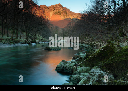 Alpenglow sur des rochers escarpés se reflète dans la rivière Derwent comme vu près de Rosthwaite dans la région des lacs de l'Angleterre Banque D'Images