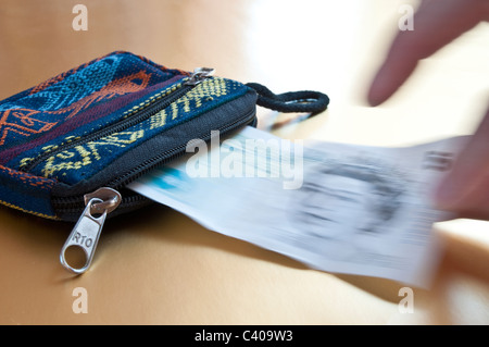 En tenant la main de femme hors d'un sac à main une note cinq livres, qui est flou Banque D'Images