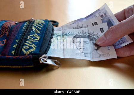 Woman's hand prendre cinq, dix et vingt livres de notes un sac à main Banque D'Images