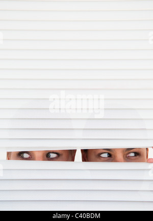 Deux femmes regarder à travers les stores Banque D'Images