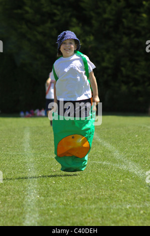 Jeune fille en compétition dans sac course sur sportsday Banque D'Images