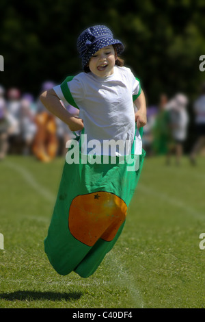 Jeune fille en compétition dans sac course sur sportsday Banque D'Images