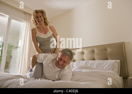 Mature couple wrestling on bed Banque D'Images