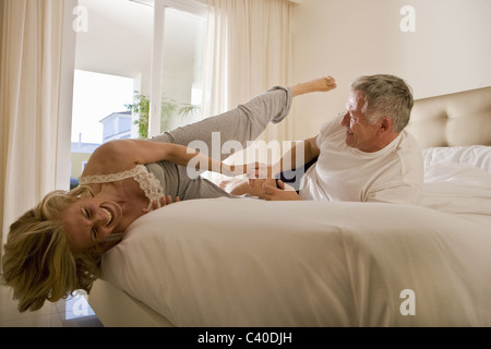 Mature couple wrestling on bed Banque D'Images