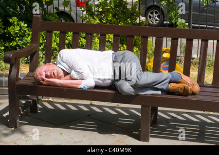 , Londres Hampstead Village , rue de l'étang par l'hôpital Royal Free , d'âge moyen aux cheveux rouges non rasé homme endormi sur le banc de parc Banque D'Images