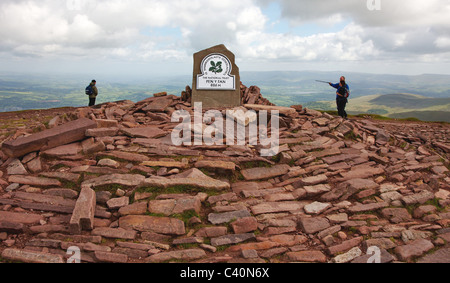 Les randonneurs d'atteindre la plaque couronnant le sommet de grès rouge vieux cairn sur Pen Y Fan dans le parc national de Brecon Beacons au Pays de Galles du Sud Banque D'Images