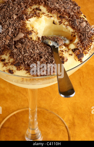 Crème vanille crème dessert au chocolat servi avec dans un verre sur un fond orange. Focus sélectif. Banque D'Images