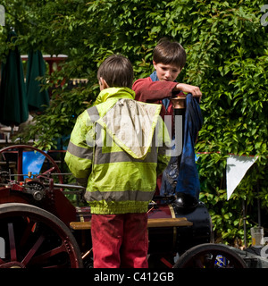 Deux jeunes garçons travaillant sur un moteur de traction à vapeur miniature. Banque D'Images