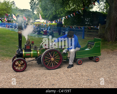 Un homme assis sur un moteur de traction à vapeur miniature à un bain à vapeur rally. Banque D'Images
