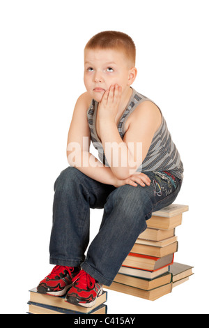 Garçon assis sur les livres de la tête dans ses mains isolé sur fond blanc Banque D'Images