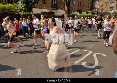 Glissières de prendre part à la Vierge 2011 Marathon de Londres vu ici à 14 miles sur une journée très chaude avec une dame dans une robe de mariage Banque D'Images