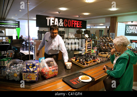 Une vieille dame se servi du café à la pause bienvenue services, Membury Autoroute, autoroute M4 Wiltshire, Royaume-Uni Banque D'Images