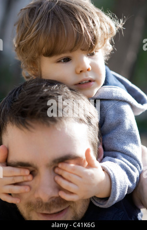 Bébé garçon couvrant les yeux du père avec ses mains, portrait Banque D'Images