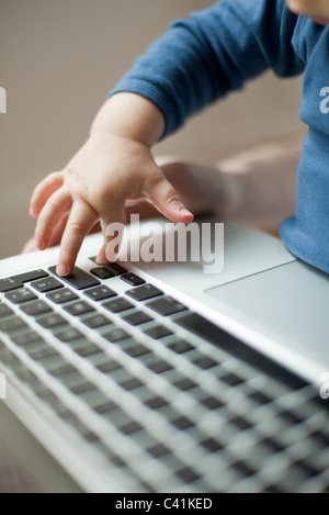 La main de l'enfant de toucher un clavier d'ordinateur portable Banque D'Images