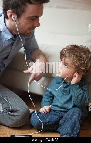 Le père et le petit garçon à l'écoute de MP3 avec écouteurs, portrait Banque D'Images