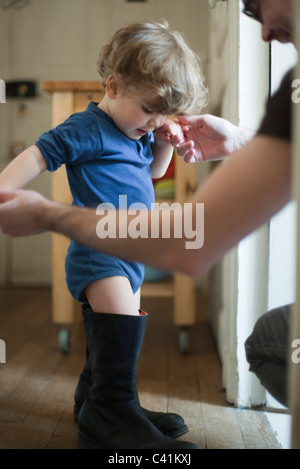 Bébé garçon apprendre à marcher dans les bottes du père Banque D'Images