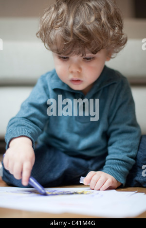 Tout-petit garçon assis sur le plancher, dessin sur papier Banque D'Images