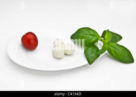 Boules de mozzarella avec tomates cerises sur une plaque blanche Banque D'Images
