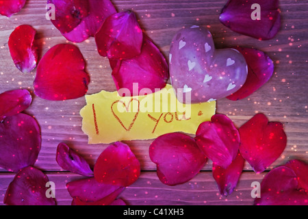 Un cœur de pierre de pétales d'une rose et d'une lettre d'amour Banque D'Images