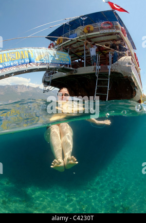 En duplex, une femme à côté du bateau d'excursion, Cleopatra Island (l'île de Sedir), sur la mer Egée, en Turquie Banque D'Images