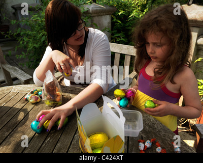 Jeune fille adolescente et tante avec Collection d'oeufs en chocolat après une chasse aux oeufs de Pâques dans le jardin de l'Angleterre Banque D'Images