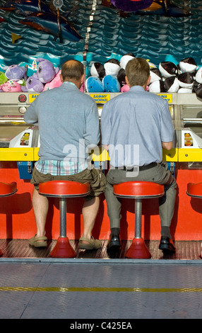 Des gens assis sur des tabourets dans un champ de foire sur la jetée de Brighton. Banque D'Images