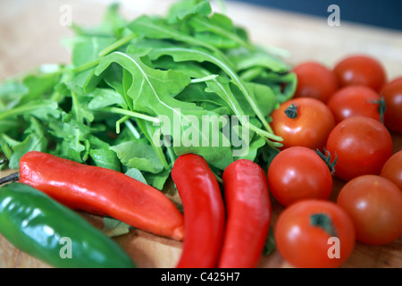 Fusée avec tomates cerises, poivrons rouges et verts sur une planche à découper en bois Banque D'Images